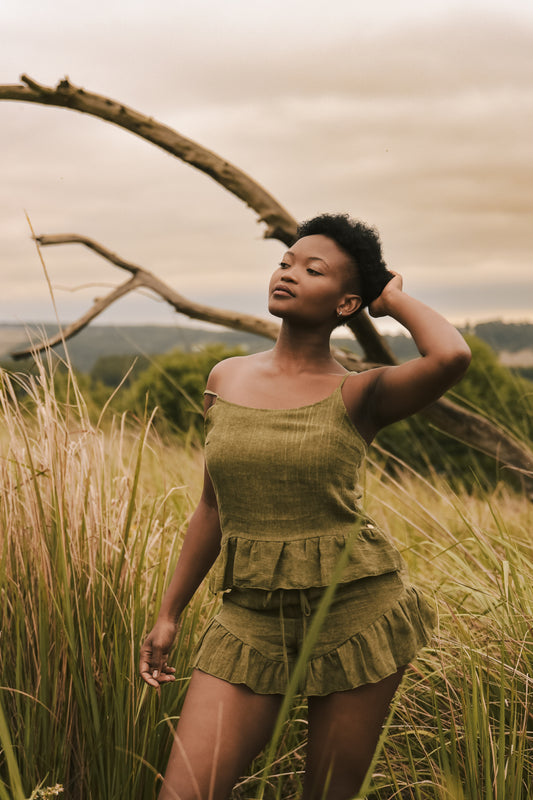 Beautiful woman standing outdoors wearing the ivy colour luxury linen loungewear set, comprised of linen top and linen shorts with elasticated waist band and friled bottom hems.