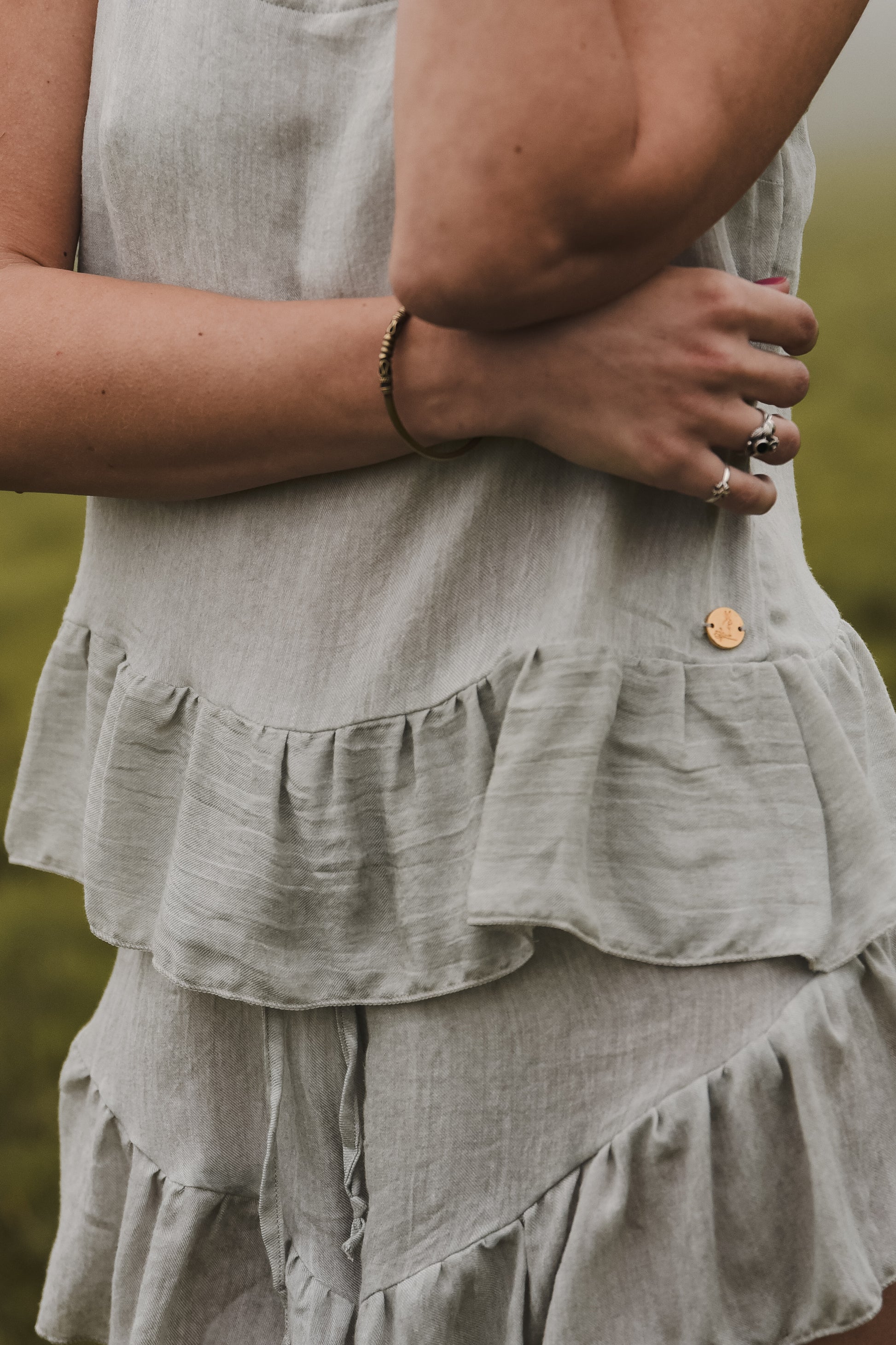 A close-up photo of the sage coloured moonflower loungewear set showcasing the bottom frilled hem on the top and the shorts.